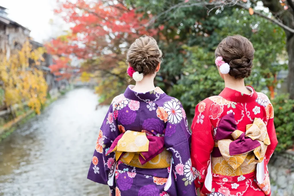 Two visitors wearing traditional kimono while walking along a canal in a historic town near Lake Biwa, Japan