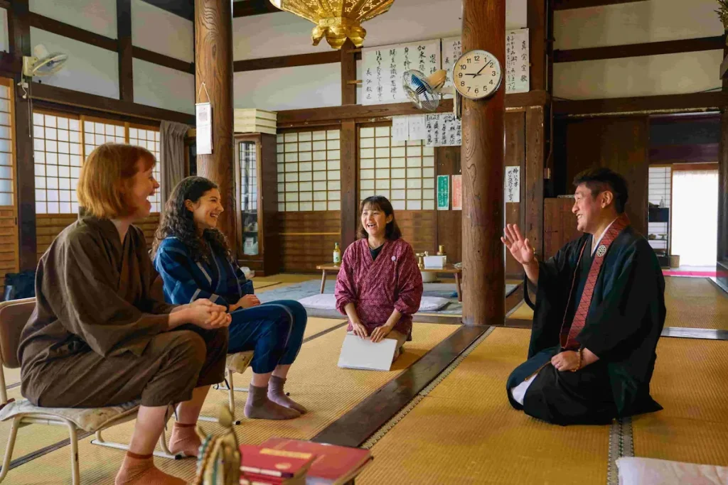 A local Buddhist priest explaining regional history and culture to visitors during a guided temple experience in Nagahama