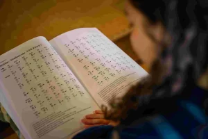 A participant learning Buddhist chanting by reading a sutra during a guided temple experience in Nagahama