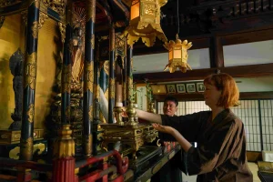 A participant offering food to a Buddhist altar as part of a guided temple cultural experience in Nagahama